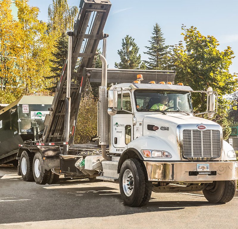 Photo of Alaska Waste roll-off truck dropping on a roll-off bin.